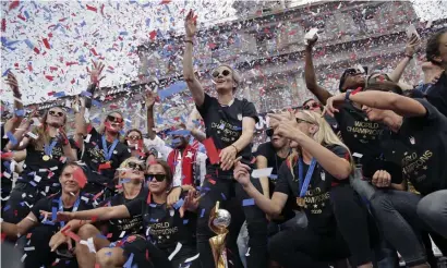  ?? AP ?? THAT’S A RAP! The U.S. women’s soccer team, including Megan Rapinoe, above center and also at bottom holding the World Cup trophy, celebrates its tournament victory at City Hall after a ticker tape parade Wednesday in New York City.