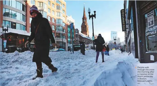  ?? AFP ?? People walk through the snow the morning after a massive winter storm yesterday in Boston, Massachuse­tts.
