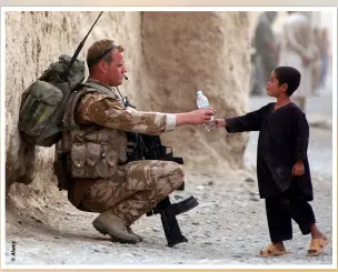  ??  ?? Senior Aircraftma­n Joe Ralph of the RAF hands a bottle of water to an Afghan child during an ISAF patrol in Kandahar Province, 19 July 2008