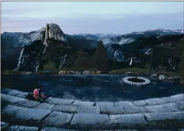  ?? MARIO TAMA — GETTY IMAGES ?? Dusk falls over Half Dome and Nevada Fall as a visitor sits June 18 in Yosemite National Park. Yosemite National Park is reopening after being closed because of unhealthfu­l air quality levels caused by wildfire smoke.