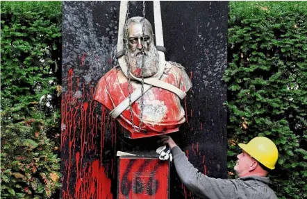  ?? — AFP ?? Splashes of anger: A worker removing a vandalised statue of Leopold in Ghent, Belgium. It was defaced amid talks to remove all statues of the king due to his misdeeds towards Congo.