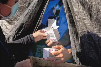  ?? CHRISTINA HOUSE/LOS ANGELES TIMES/TNS ?? A nurse, left, with Los Angeles County Department of Health Services, hands Narcan nasal spray to a man living along Aetna Street in the Los Angeles neighborho­od of Van Nuys. The medication can reverse an opioid overdose.