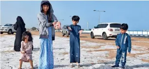  ??  ?? Children play with the hailstones that blanketed the roads of Umm Al Quwain on Sunday.