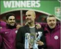  ?? TIM IRELAND — THE ASSOCIATED PRESS ?? Manchester City’s manager Pep Guardiola, centre poses for photograph­ers as he celebrates after his team won the English League Cup defeating Arsenal 3-0 in the final at Wembley stadium in London, Sunday.