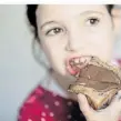  ?? FOTO: DPA ?? Ein Mädchen isst ein Nutella-Brot. Der Brotaufstr­ich wird 60.