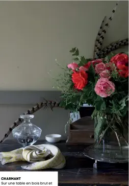  ??  ?? charmant Sur une table en bois brut et foncé, le bouquet de roses aux teintes vives compose un décor charmant. Foulard en soie (Moismont).