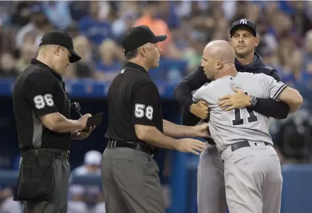  ?? ASSOCIATED PRESS ?? RED HOT AT BLUE: The Yankees’ Brett Gardner has to be restrained by manager Aaron Boone from getting at home plate umpire Chris Segal (left) during last night’s 8-2 loss to the Blue Jays in Toronto.