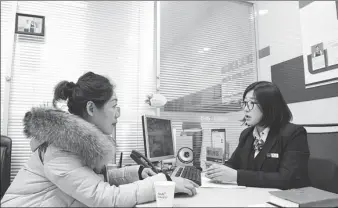  ?? XINHUA ?? A bank employee addresses customer queries on wealth management in Hohhot, Inner Mongolia autonomous region.
