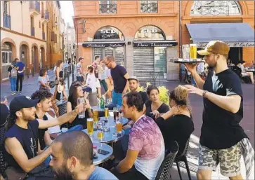  ?? Chris O’Brien For The Times ?? A WAITER brings another round of beer to a group of friends at a bar in Trinity Plaza in Toulouse, France.