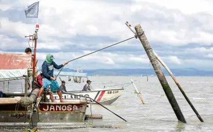  ?? —LYN RILLON ?? DOWNIT GOES Ademolitio­n team member pulls down a post of a fish pen in Laguna de Bay on Thursday. The lake is being cleared of obstructio­ns on orders of President Duterte.