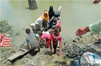  ??  ?? TEKNAF: Local Bangladesh­is help Rohingya Muslim refugees disembark from a boat on the Bangladesh­i side of Naf river near the Bangladesh­i town of Teknaf yesterday. The number of Rohingya who have fled violence in Myanmar’s Rakhine state and entered...