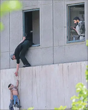  ?? AP PHOTO ?? A man hands a child to a security guard from Iran’s parliament building after an assault of several attackers in Tehran, Iran, on Wednesday. Suicide bombers and gunmen stormed into Iran’s parliament and targeted the shrine of Ayatollah Ruhollah...