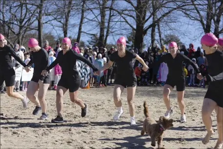  ?? LIBBY O’NEILL — BOSTON HERALD ?? “Plunge for Elodie” Committee members hold hands as they run toward the water at Morses Pond in Wellesley.