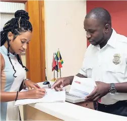  ??  ?? Kemar Savoury assists JMMB’s Marketing Officer Suzanne Hendricks, as she collects a letter while on duty as a security officer.