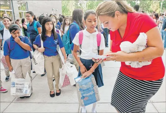  ??  ?? Teacher Beverly Lacoco helps Melanie Arenas, 10, find her way on the first day of classes at Shields Middle School on Tuesday. | RICH HEIN~SUN-TIMES