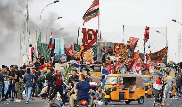  ?? Reuters ?? ↑ Iraqi demonstrat­ors block Al Sanak Bridge during the anti-government protests in Baghdad on Monday.