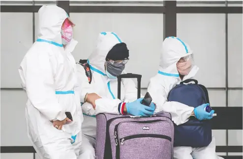  ?? DARRYL DYCK / THE CANADIAN PRESS FILES ?? If you’re thinking of travelling, even with protective face masks, goggles and Tyvek suits like this group in Vancouver, don’t do it, says the prime minister, who hinted new measures may be coming.