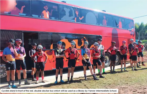  ?? ?? Cyclists stand in front of the red, double decker bus which will be used as a library by Yarrow Intermedia­te School.