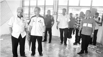  ??  ?? Masing (left) inspects an unfurnishe­d classroom.