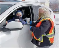  ??  ?? Heidi Slyngbom, a volunteer with the Peachland Recovery Task Force, hands over hot chocolate to Louise MacNamara, who wanted to come out and support the event.