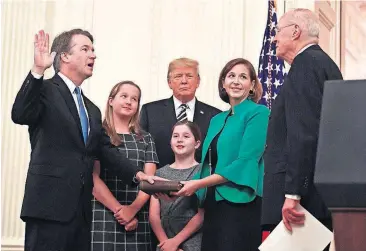  ?? [AP PHOTO] ?? President Donald Trump, center, listens as retired Supreme Court Justice Anthony Kennedy, right, ceremonial­ly swears-in Supreme Court Justice Brett Kavanaugh, left, in the East Room of the White House on Monday in Washington. Kavanaugh’s wife Ashley watches, second from right with daughters Margaret, left, and Liza.