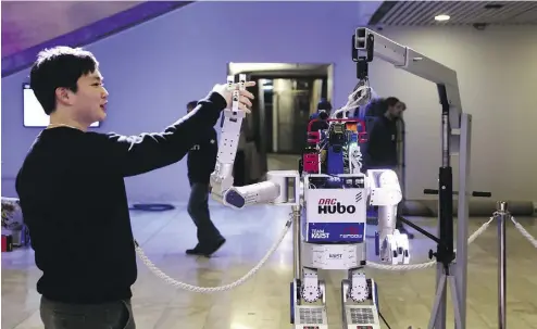  ?? SIMON DAWSON / BLOOMBERG NEWS ?? A prize-winning South Korean robot called HUBO struts its stuff amid a crowd of camera- clicking delegates in Davos, Switzerlan­d. It is also stoking fears about the impact of robotics on employment.