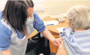  ??  ?? Roll-out Fay Mackay receives the vaccine, and below, she gives it the thumbs up