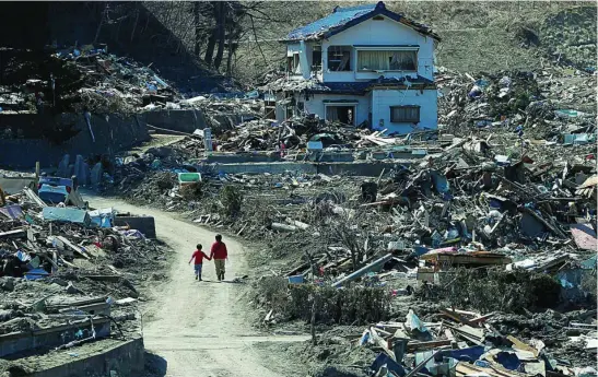  ?? REUTERS ?? Dos personas pasean por un área devastada el 11 de marzo de 2011 por el terremoto y el posterior tsunami en la prefectura japonesa de Fukushima