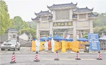  ?? — AFP photo ?? People wearing protective suits as a preventive measure against the Covid-19 coronaviru­s control an access point to the Biandansha­n cemetery in Wuhan in China’s central Hubei province. As China’s coronaviru­s epicentre of Wuhan awakens from its long nightmare, formerly locked-down citizens are beginning to re-emerge, but for many their first outdoor act in more than two months is grim: burying loved ones.