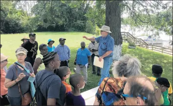  ?? TED SLOWIK/DAILY SOUTHTOWN ?? Historian Larry McClellan, center, tells a tour group on July 20 how a present-day marina along the Little Calumet River was the site of Ton Farm.