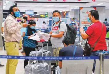  ?? AFP ?? Indians, returning from Dubai on a special flight, wait for a medical check before being taken to a quarantine facility, at the Amritsar internatio­nal airport in Punjab.