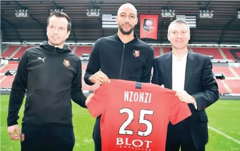 ?? AFP ?? Rennes’ newly recruited midfielder Steven Nzonzi (centre) flanked by Rennes’ French coach Julien Stephan (left) and Rennes’ president Olivier Letang poses with his jersey at the Roahzon Park stadium in Rennes, western France.