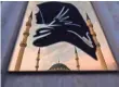  ?? KIRILL KUDRYAVTSE­V, AFP/GETTY IMAGES ?? A view of the Heart of Chechnya mosque is reflected on a metal panel with the silhouette of a woman wearing a scarf in central Grozny.