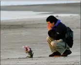  ??  ?? „ A man prays after offering flowers in Arahama coastal area where the tsunami struck in 2011.