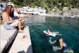  ??  ?? Les enfants passent une bonne partie de la journée dans l’eau, devant le quai, au pied des cabanons.