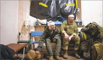 ?? Evgeniy Maloletka Associated Press ?? UKRAINIAN servicemen wait Sunday to leave a field hospital near Bakhmut, where intense fighting has continued. One Ukrainian military analyst said the Russian offensive in the east has become bogged down.