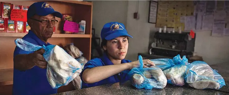  ??  ?? Workers package bread to sell at a bakery in Caracas in March. — WP-Bloomberg photos