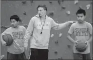  ?? NWA Democrat-Gazette/DAVID GOTTSCHALK ?? Elliot Bailey (center), seventh-grade basketball coach at Sonora Middle School, reviews Friday a three-person passing drill with his seventh-grade team at the school.