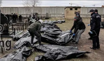  ?? ?? Workers lined up bodies for identifica­tion by forensic personnel and police officers in the cemetery in Bucha, north of Kyiv after hundreds of civilians were found dead in areas from which Russian troops have withdrawn around Kyiv, including the town of Bucha.