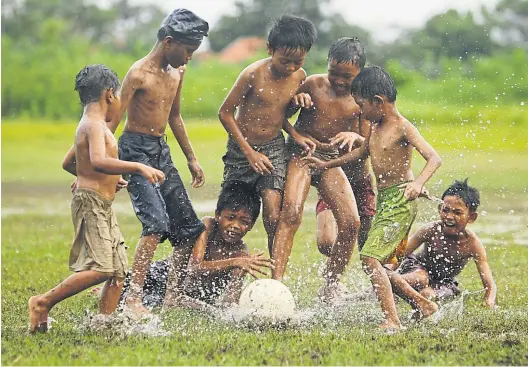  ?? Reuters ?? Spaß am Spiel, Liebe zum Fußball, Lachen – in Südostasie­n braucht es zumeist keinen gepflegten Rasen, kein Stadion. Gespielt wird überall.