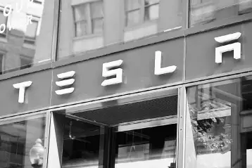  ?? — AFP photo ?? In this file photo, the Tesla logo is seen outside of their showroom in Washington, DC. Tesla CEO Elon Musk said in a blog posting Friday, August 24, that his company would continue to be publicly traded, weeks after suggesting that he would take the electric carmaker private.