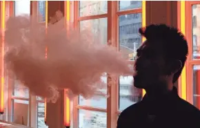  ?? FRANK FRANKLIN II/AP ?? A customer exhales vapor from an e-cigarette at a store in New York. A growing number of e-cigarette and vaporizer sellers have started offering college scholarshi­ps.