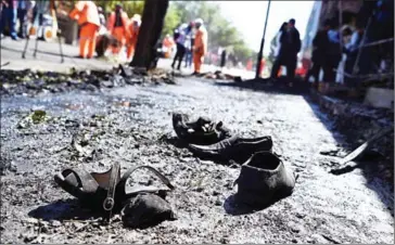  ?? WAKIL KOHSAR/AFP ?? The shoes of victims are seen on the ground as Afghan residents inspect the site of a car bomb attack in western Kabul yesterday.