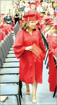  ??  ?? Farmington graduate Emily Estrada returns to her seat with diploma in hand, the culminatio­n of 12 years of schooling during Farmington High School graduation ceremonies at Cardinal Arena.