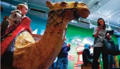  ??  ?? Alison Pilgrim, from Melbourne, Australia, right, makes a photo of her daughter Eve Pilgrim, 2, left, seated on a replica of a Sahara camel at a show called "America to Zanzibar: Muslim Cultures Near and Far," at the Children's Museum of Manhattan in...