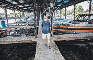  ?? ZBIGNIEW BZDAK/CHICAGO TRIBUNE ?? Navy Point Point Marine co-owner Peter Leubner walks his docks July 31 at Sackets Harbor, New York. He said in 2017 he was forced to shut down the power to the marina as waves crashed in, causing the loss of 35 slips.