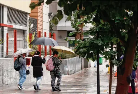  ?? Jessica Christian/The Chronicle ?? A family walks across Folsom Street as rain falls in San Francisco on Tuesday. Rain has become more frequent along the coast.