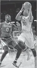  ?? CHARLIE NEIBERGALL/THE ASSOCIATED PRESS ?? Iowa State guard Deonte Burton, right, drives past Baylor forward Jo Lual-Acuil Jr. on Saturday in Ames, Iowa. Burton scored 22 points as Iowa State won its fifth straight.