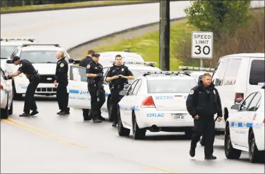  ?? Mark Humphrey / Associated Press ?? Nashville police officers gather alongside a wooded area as they search for a shooting suspect near a Waffle House restaurant in Nashville, Tenn. At least four people died after a gunman opened fire at the restaurant early Sunday.