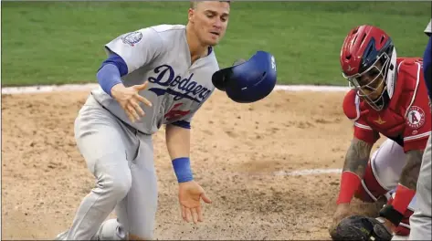  ?? AP PHOTO/MARK J. TERRILL ?? Los Angeles Dodgers’ Enrique Hernandez, left, scores on a single by Justin Turner after Los Angeles Angels catcher Martin Maldonado made a late tag during the fifth inning of a baseball game Saturday, in Anaheim.